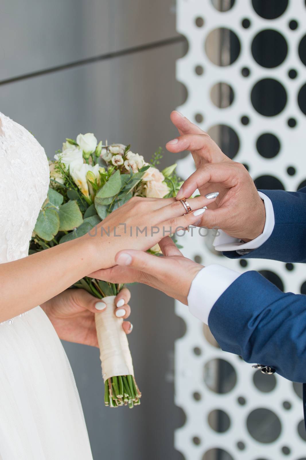 Wedding day. The groom places the ring on the bride's hand.