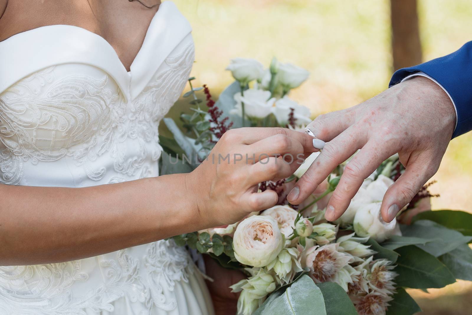 The groom places the ring on the bride's hand. Photo closeup by 3KStudio