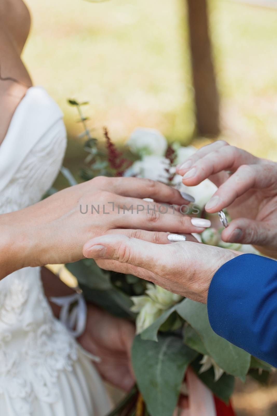 The groom places the ring on the bride's hand. Photo closeup by 3KStudio