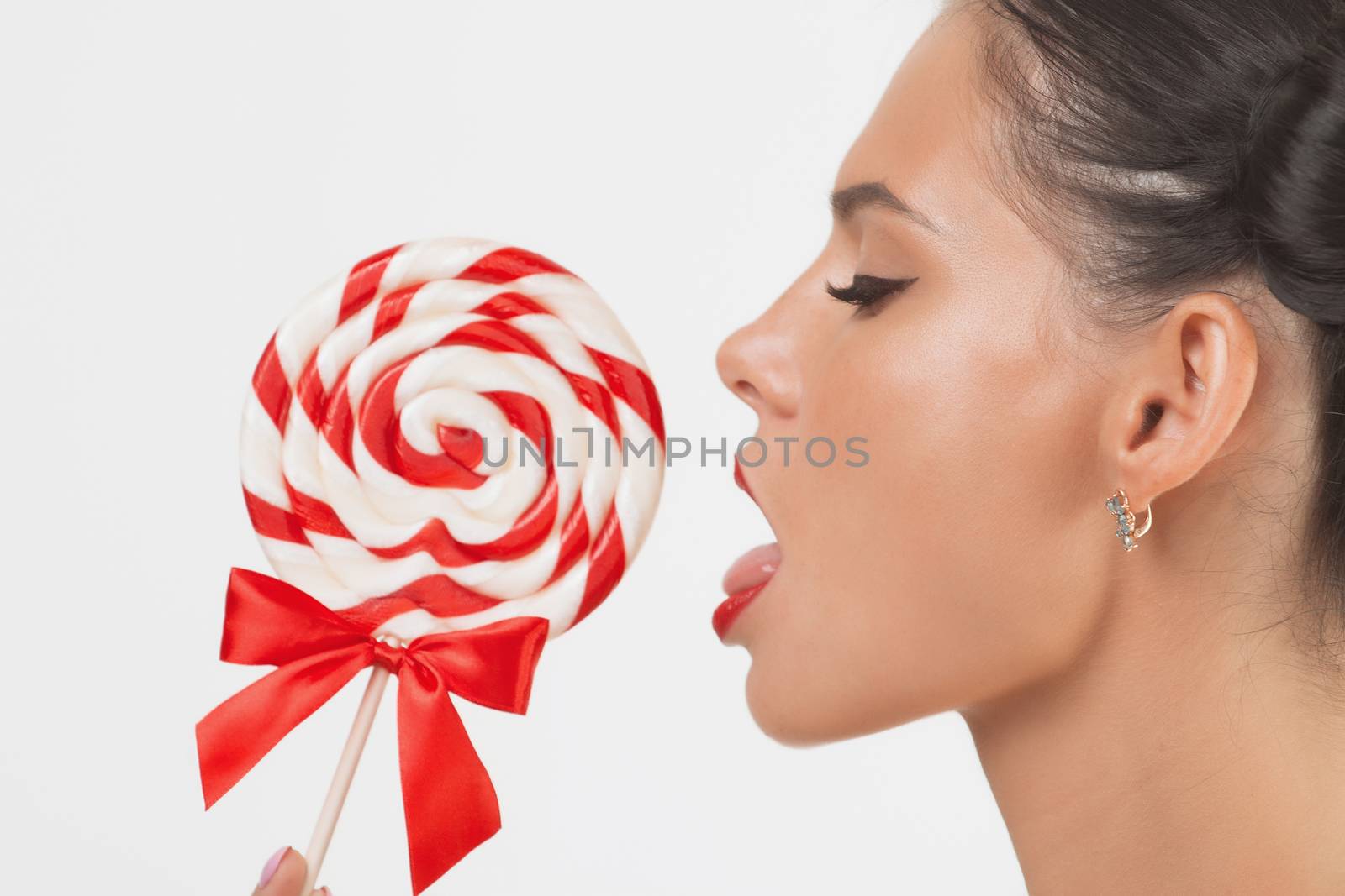 Close-up of beautiful girl's lower part of face. lips are sliding over big lollipop.