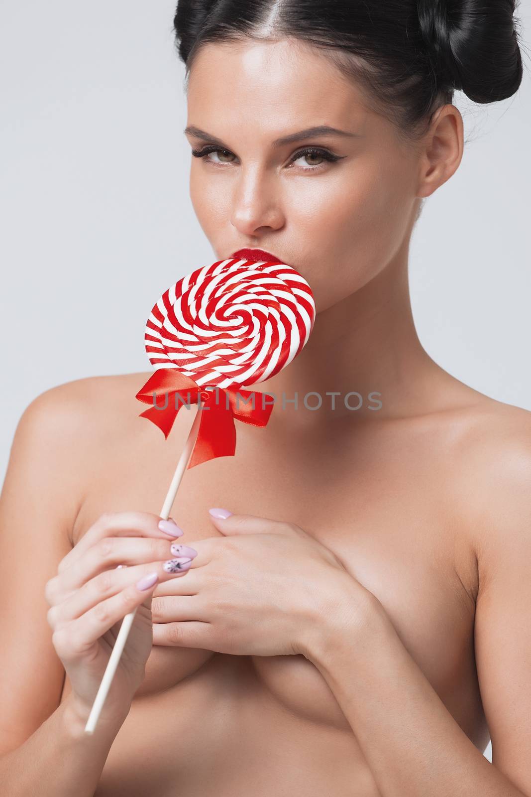 Close-up of beautiful girl's lower part of face. lips are sliding over big lollipop.