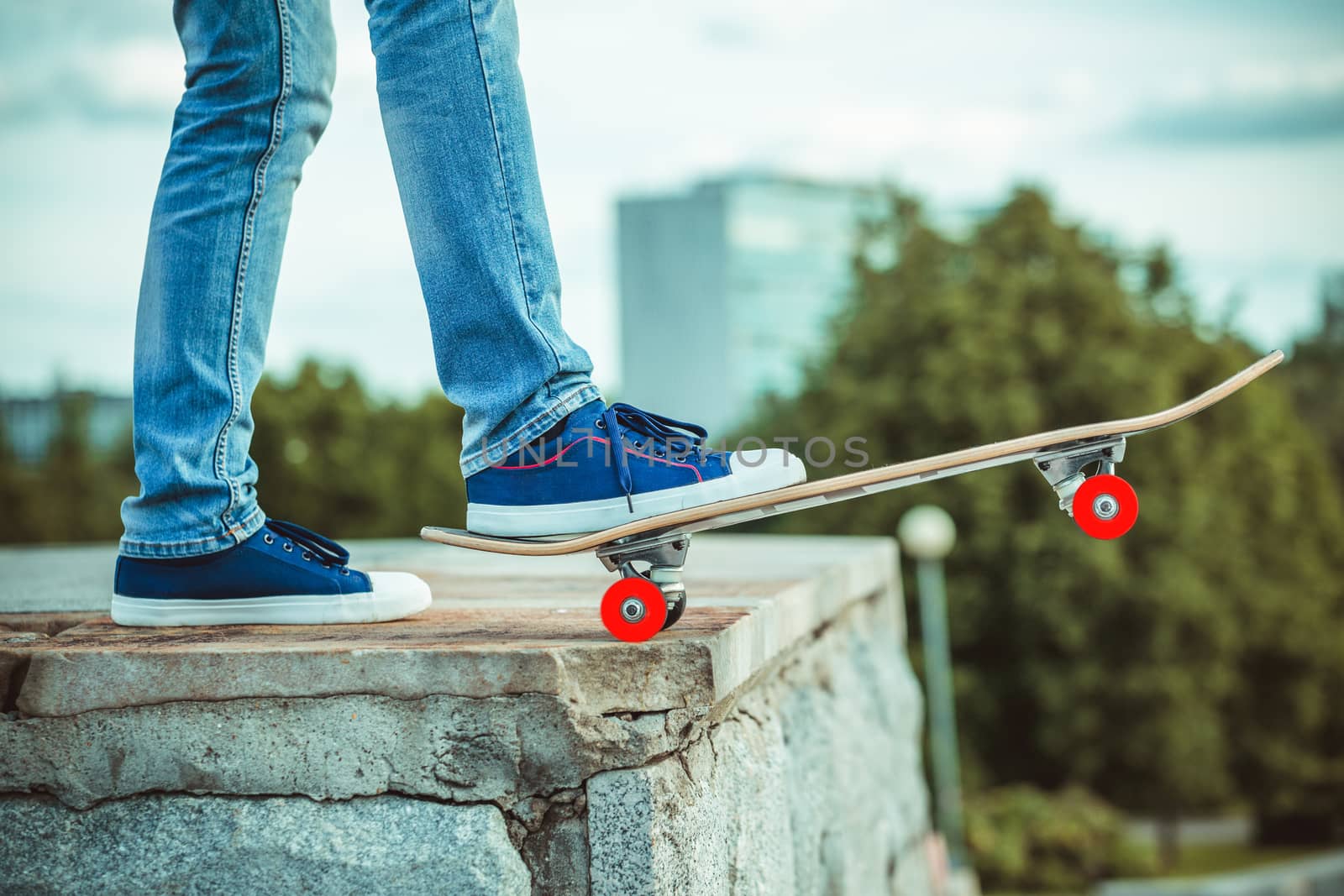 male feet in blue trainers and skateboard close up.