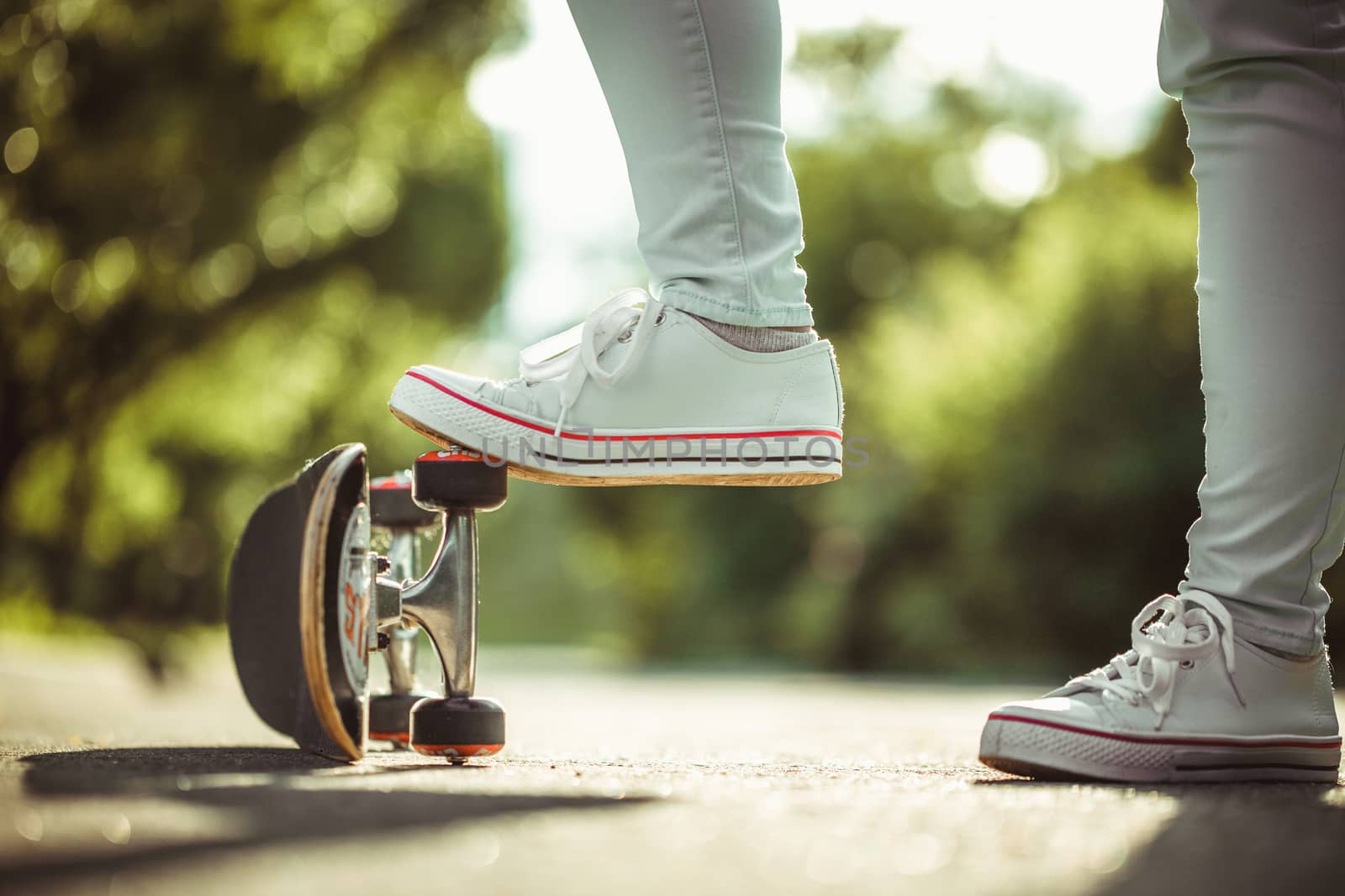 female feet in white sneakers and skateboard close up