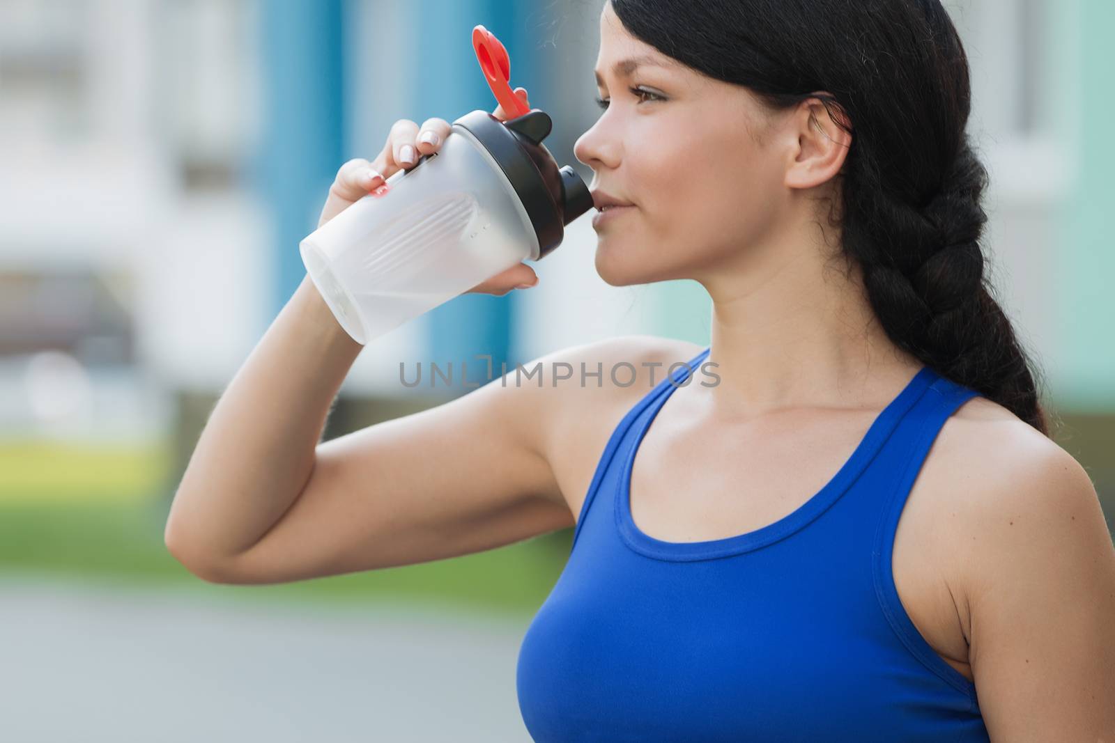 Beautiful fitness athlete woman resting drinking water after work out exercising on beach summer evening in sunny sunshine outdoor portrait by 3KStudio