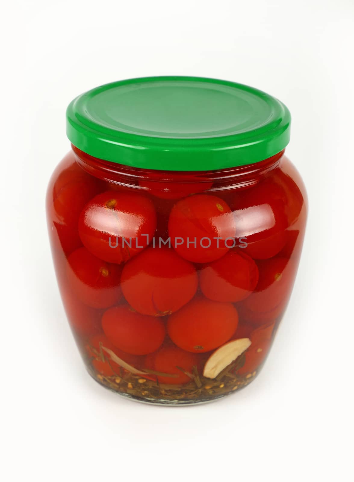 Close up of one glass jar of pickled small red cherry tomatoes with green lid over white background, high angle view