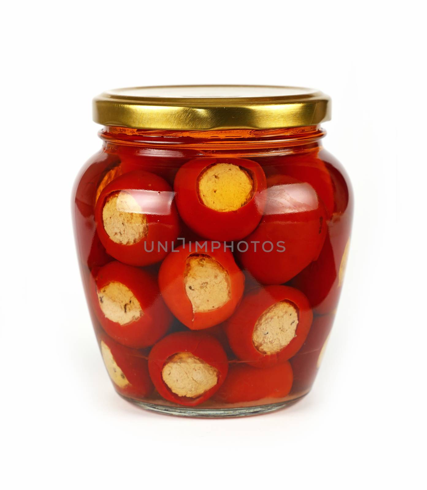 Close up of one glass jar of pickled red hot cherry chili pepperoncini peppers stuffed with soft ricotta cheese, with golden lid over white background, low angle side view