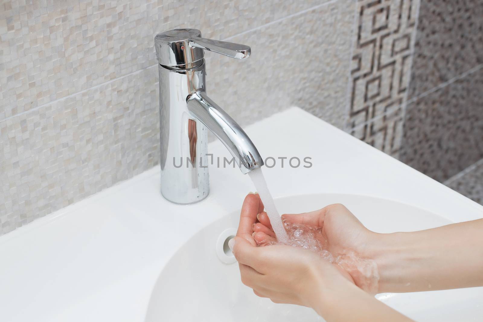 Washing of hands with soap under running water.