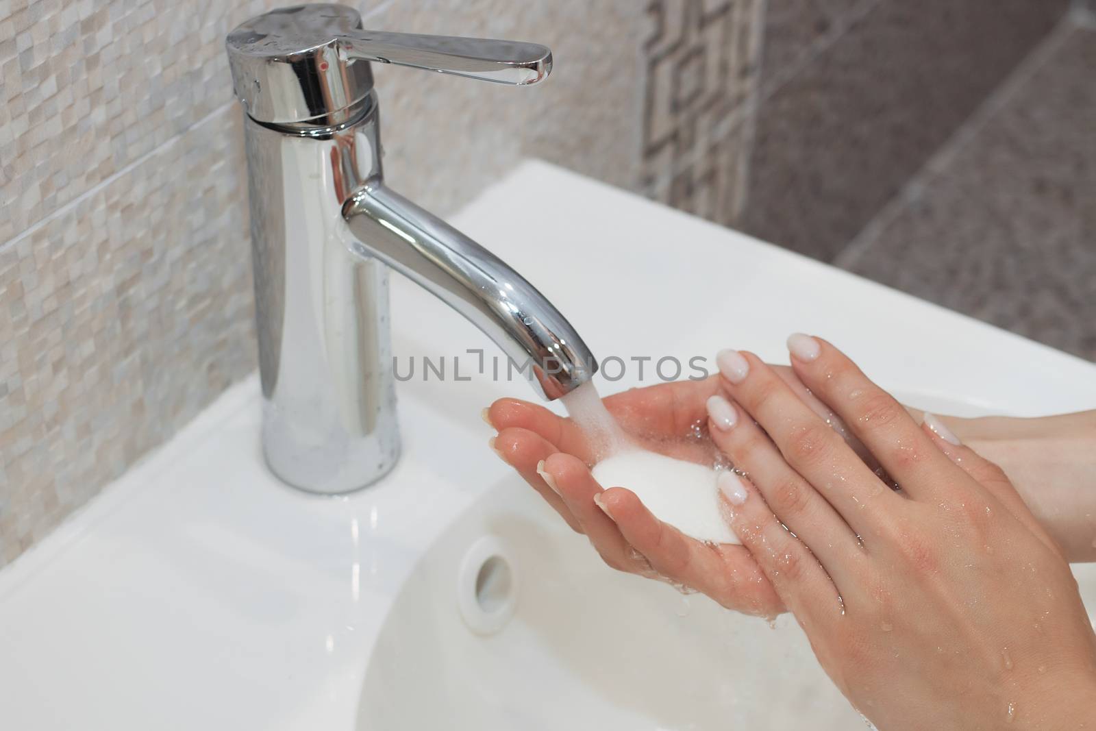 Washing of hands with soap under running water.