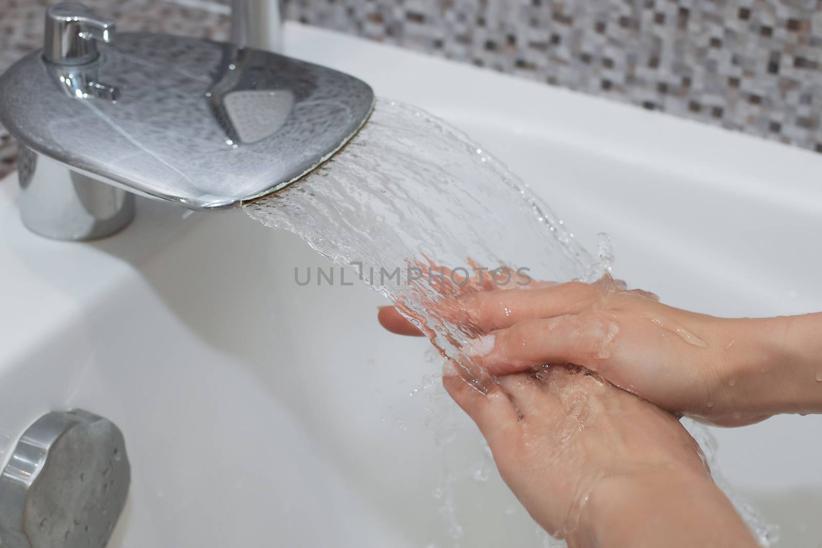 Washing of hands with soap under running water.