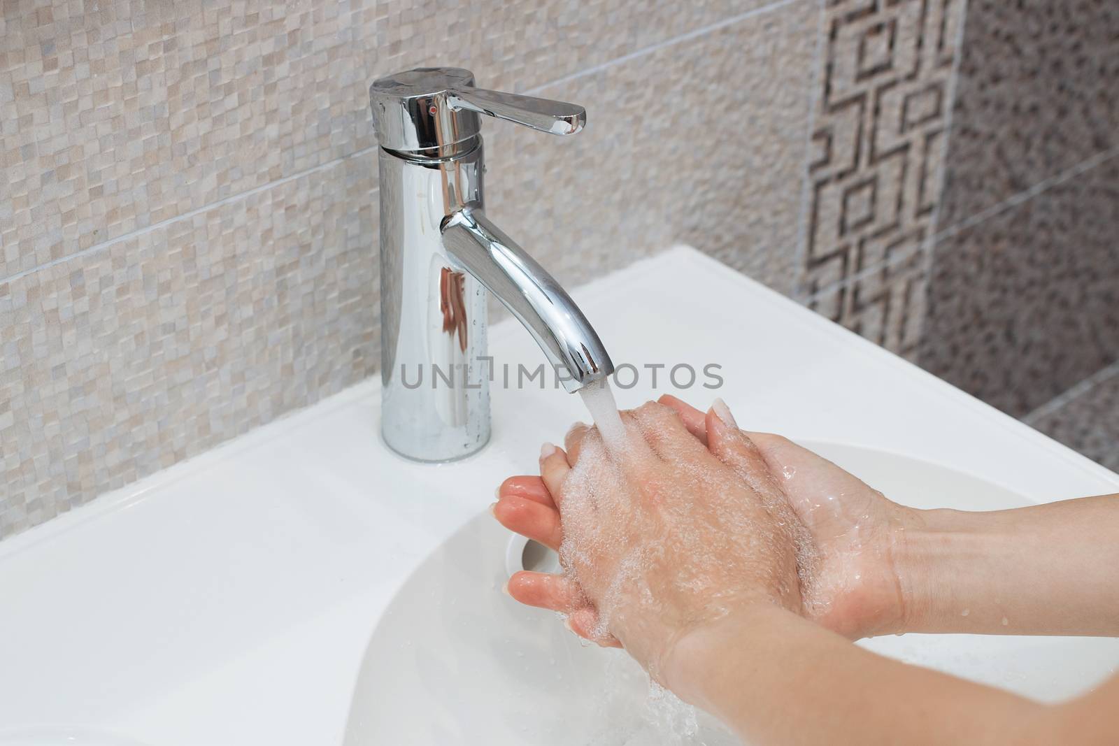 Washing of hands with soap under running water.