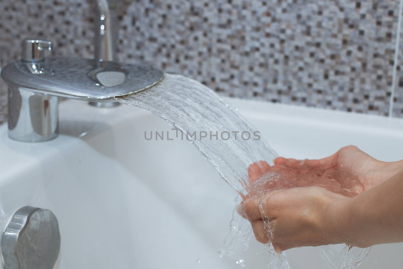 Washing of hands with soap under running water.