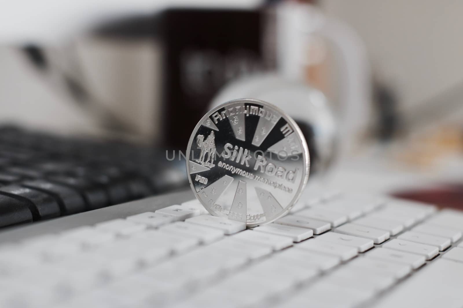 Digital currency physical metal bitcoin coin on the white keyboard near glass ball.