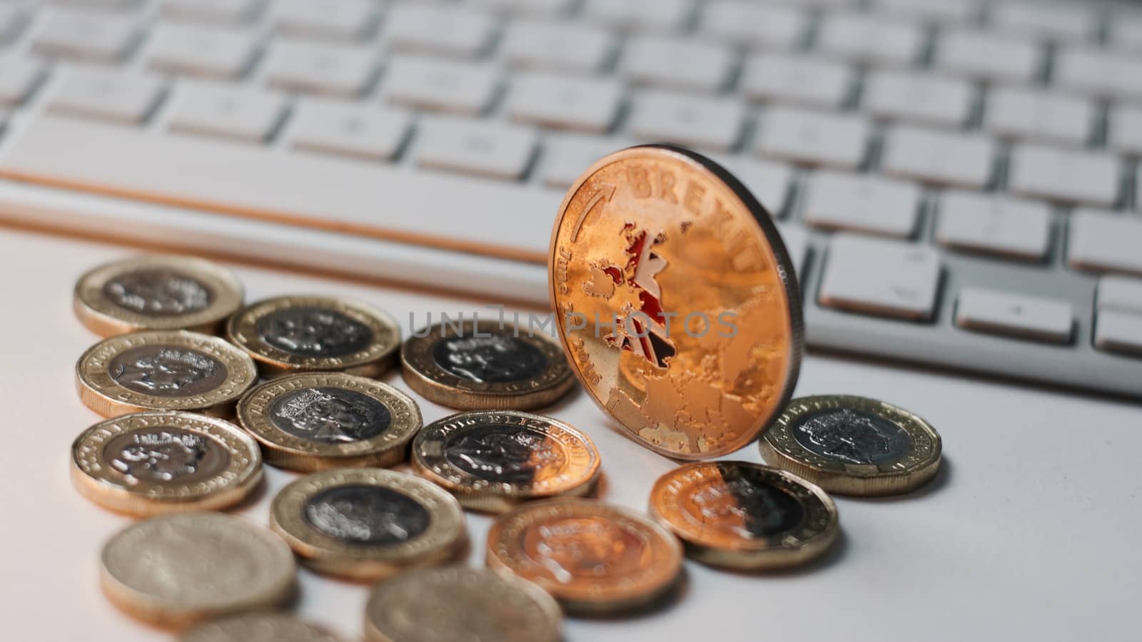 Europe leaving. Gold brexit coin with British map near keyboard and pound sterling.