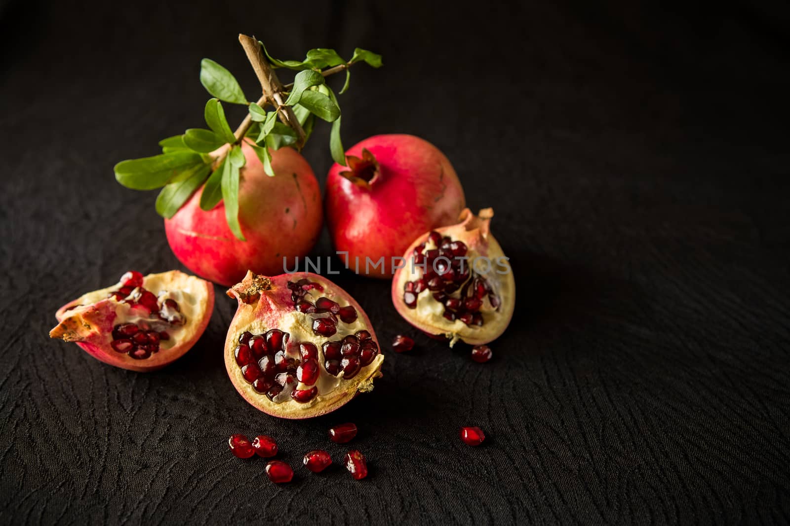Pomegranate fruits and seeds over a textured black background