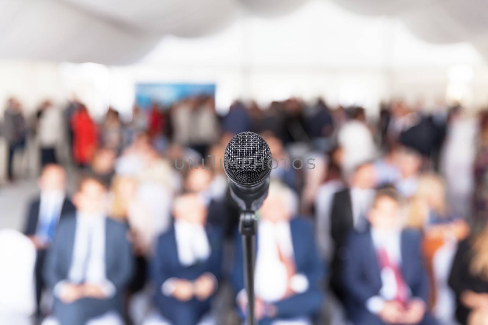 Microphone in focus against blurred audience. Participants at the business or professional conference.