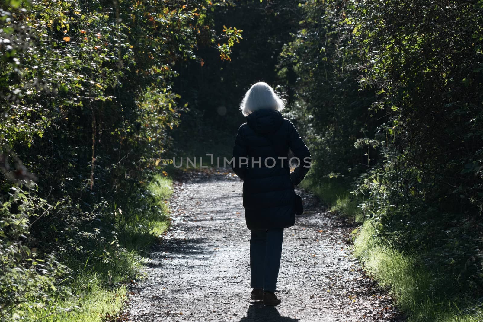 Senior woman walks alone by riverheron_photos