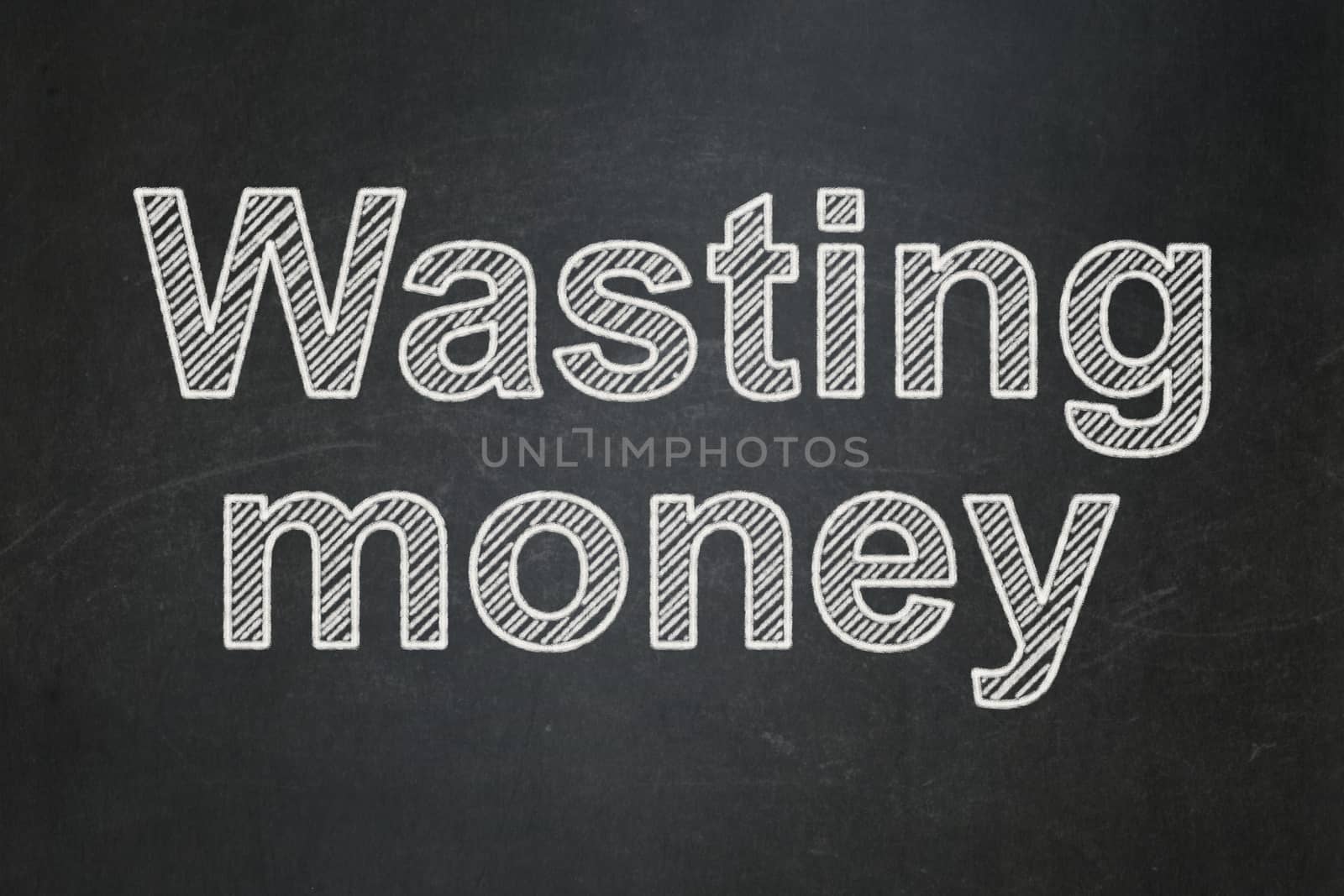 Money concept: text Wasting Money on Black chalkboard background