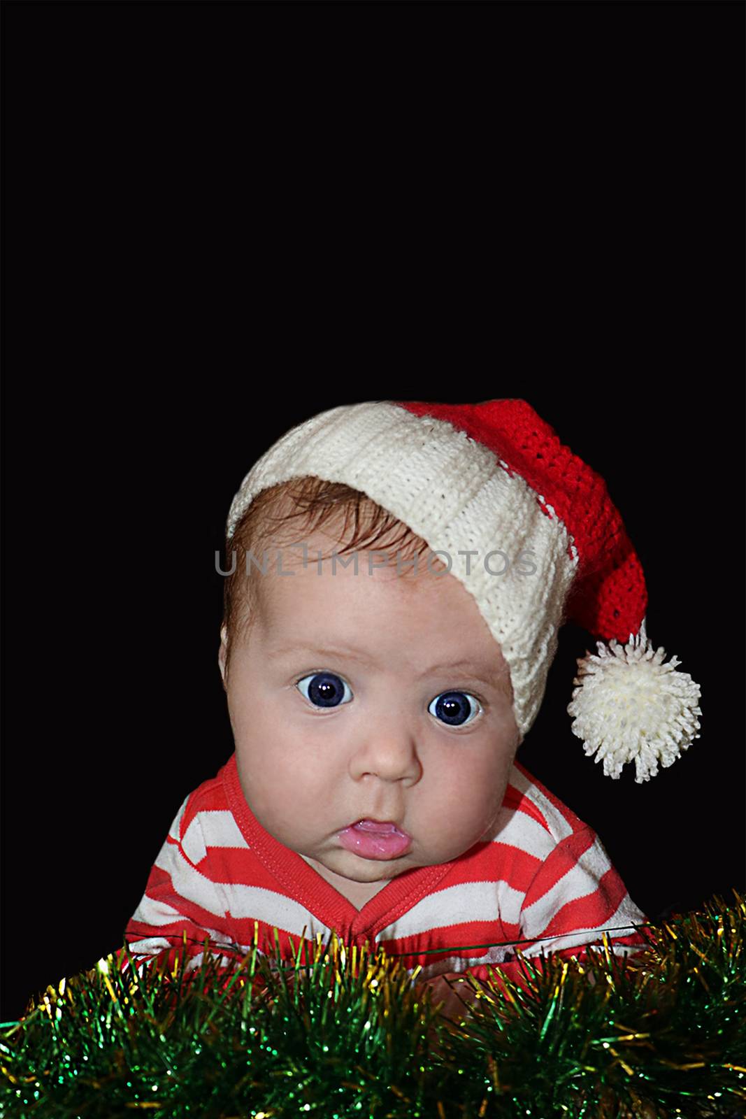 Newborn funny Santa baby with dumbfounded face isolated on black background.  Can be used for design of banners, flyers, calendars, invitations  as clip art. Place for text. 