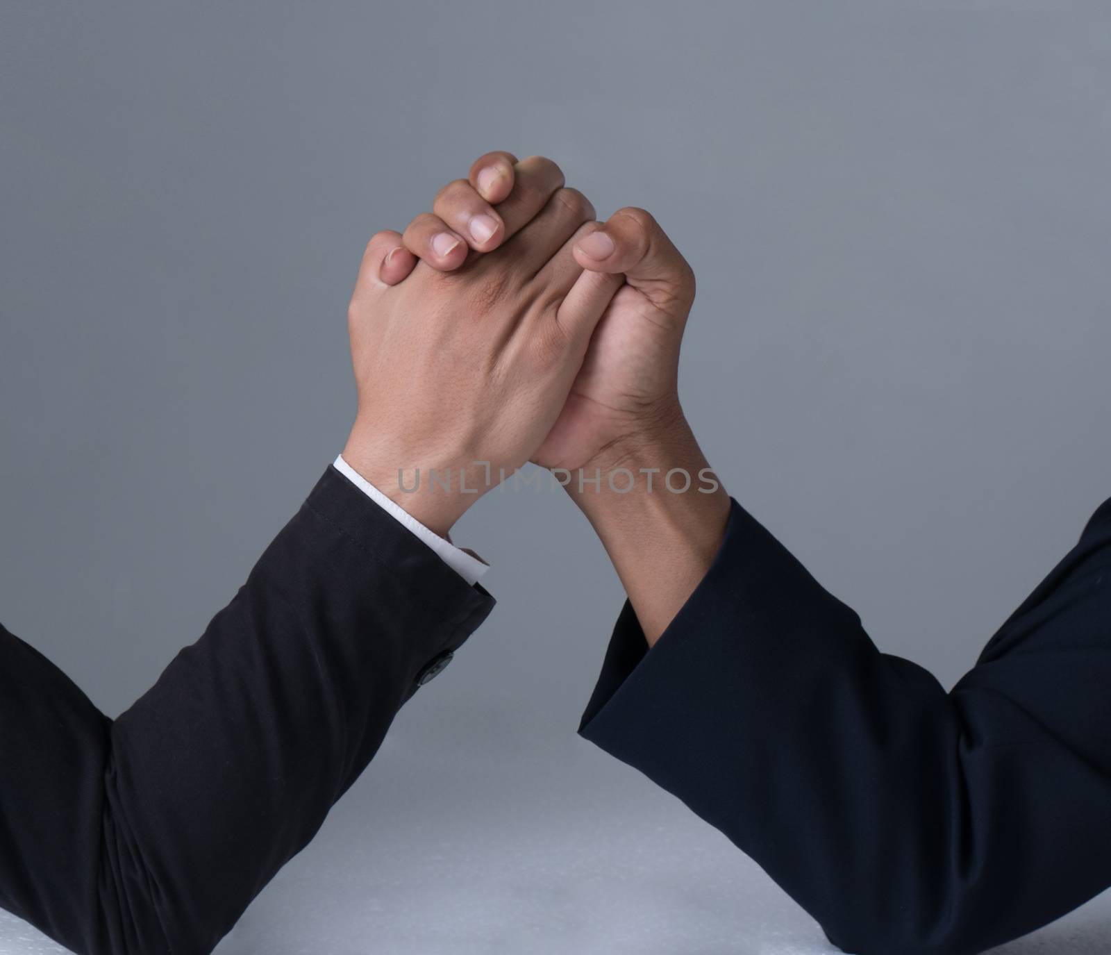 businessman engaged in arm wrestling  on gray background