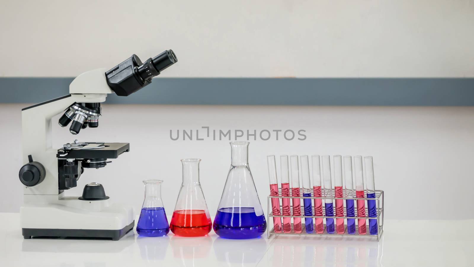 Laboratory research, flask containing chemical liquid with microscope