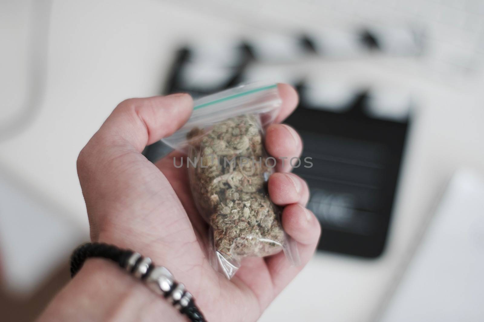 Green dry marijuana in man hand on the blurry background. Weed concept.
