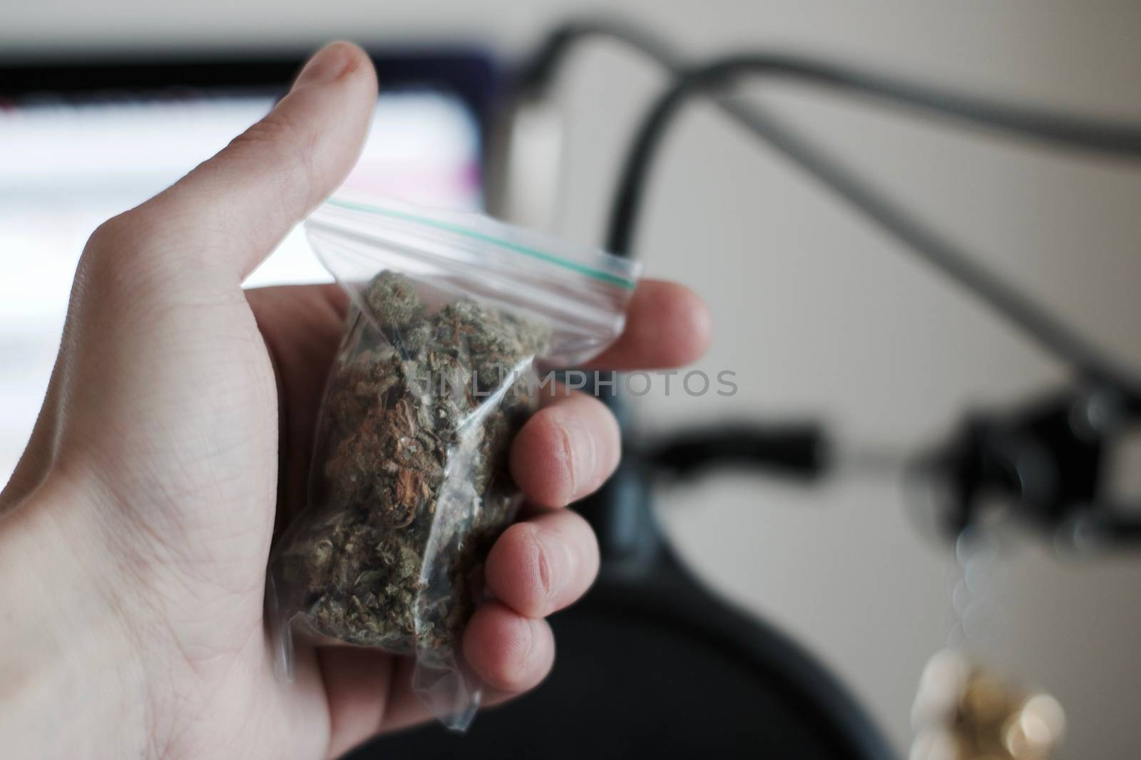 Green dry marijuana in man hand on the blurry background. Weed concept.