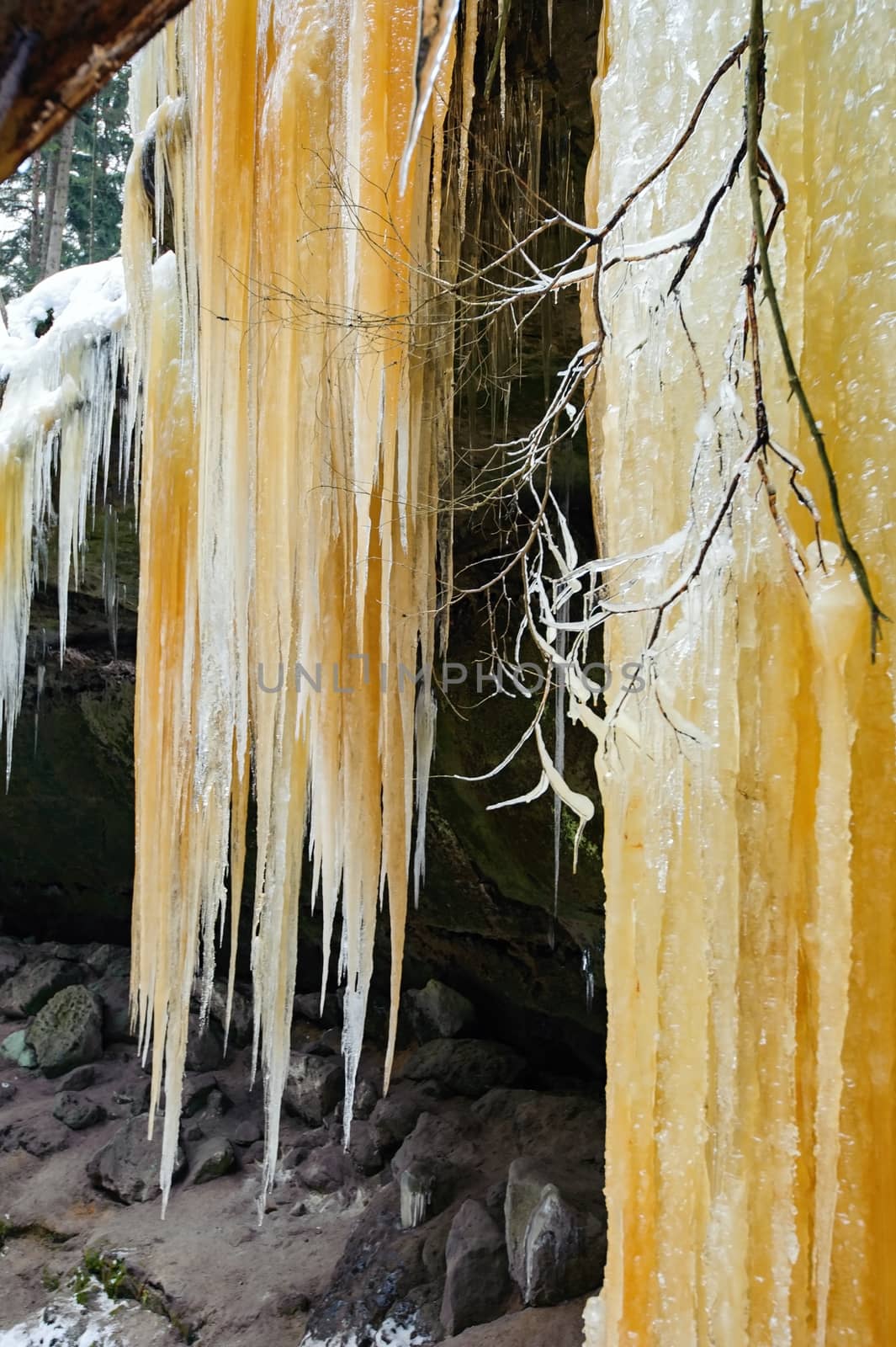 Frozen waterfalls on the rock, orange colored and snow