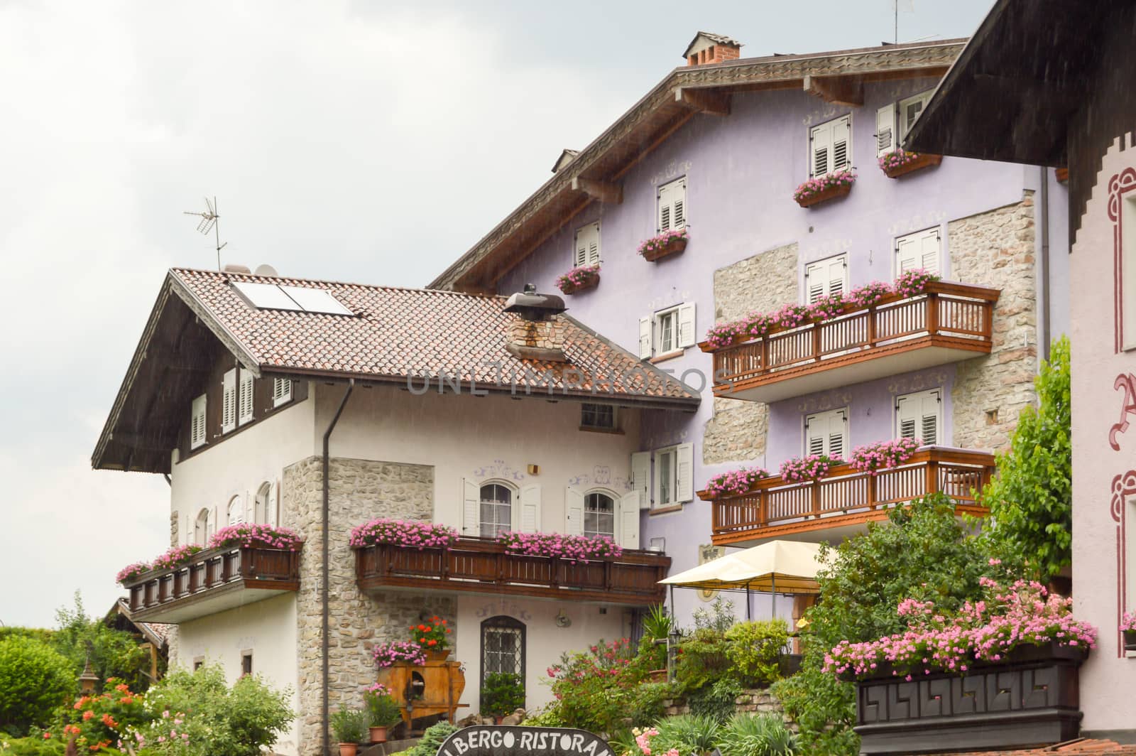 Mauve colored building with several balconies flourished in the dolomites in Italy