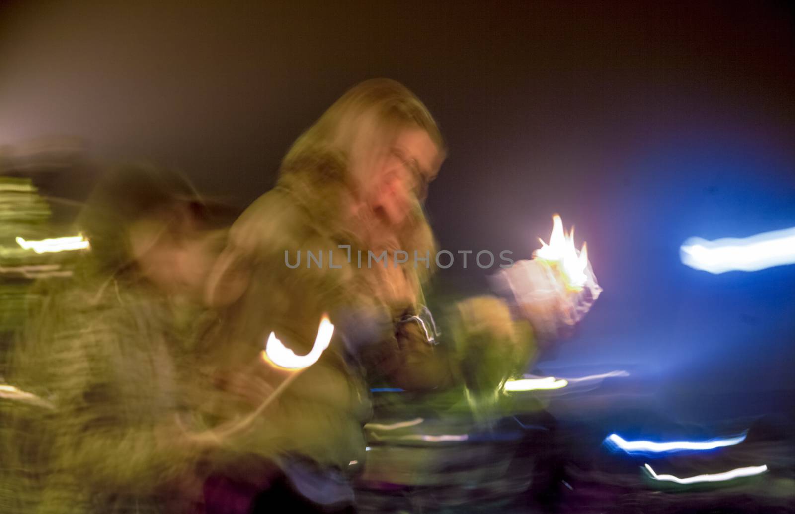 A blurred image of people with candles in their hands mourning or celebrating outdoors. Night.