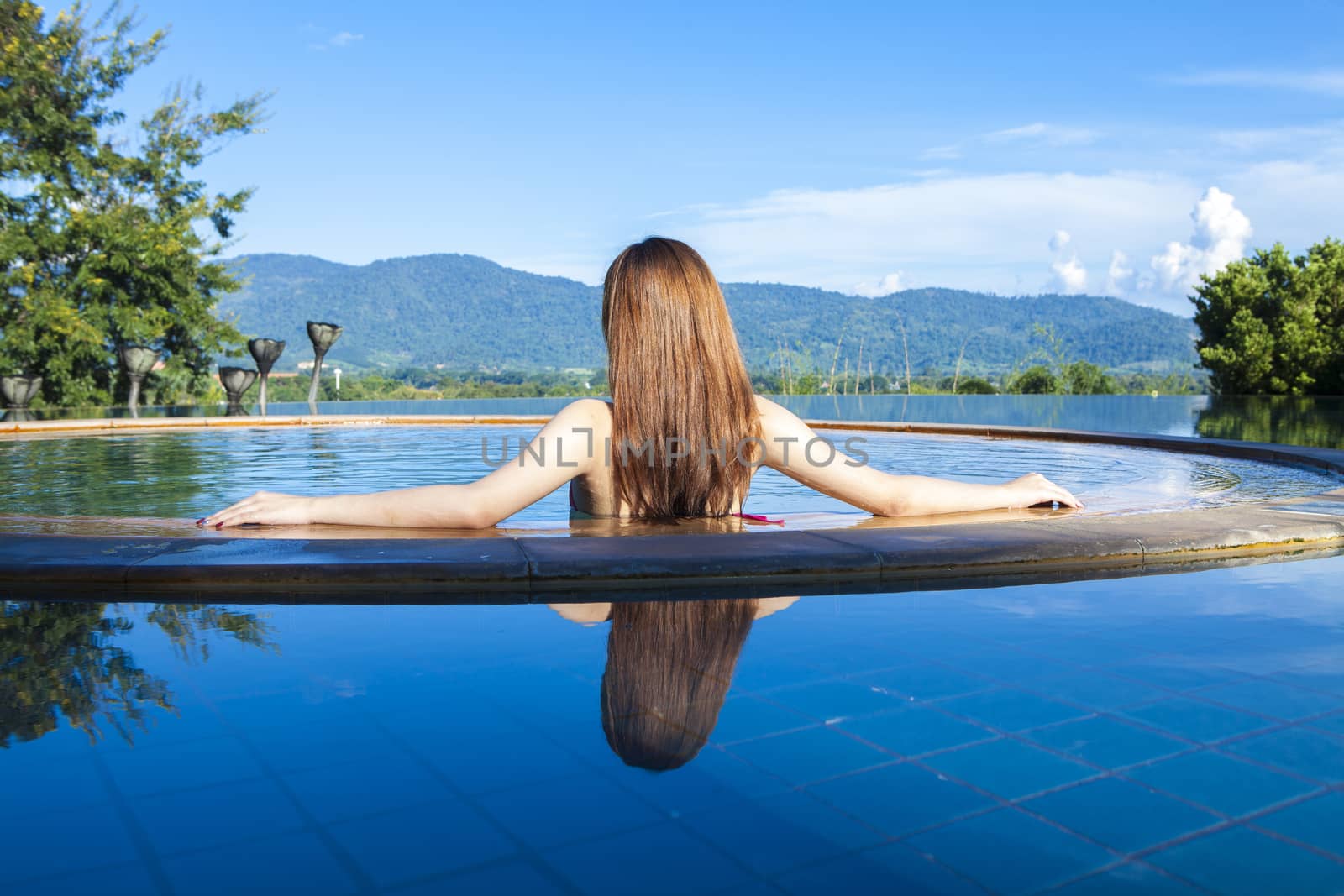 Woman relaxing in infinity swimming pool looking at view,Morning woman at the pool