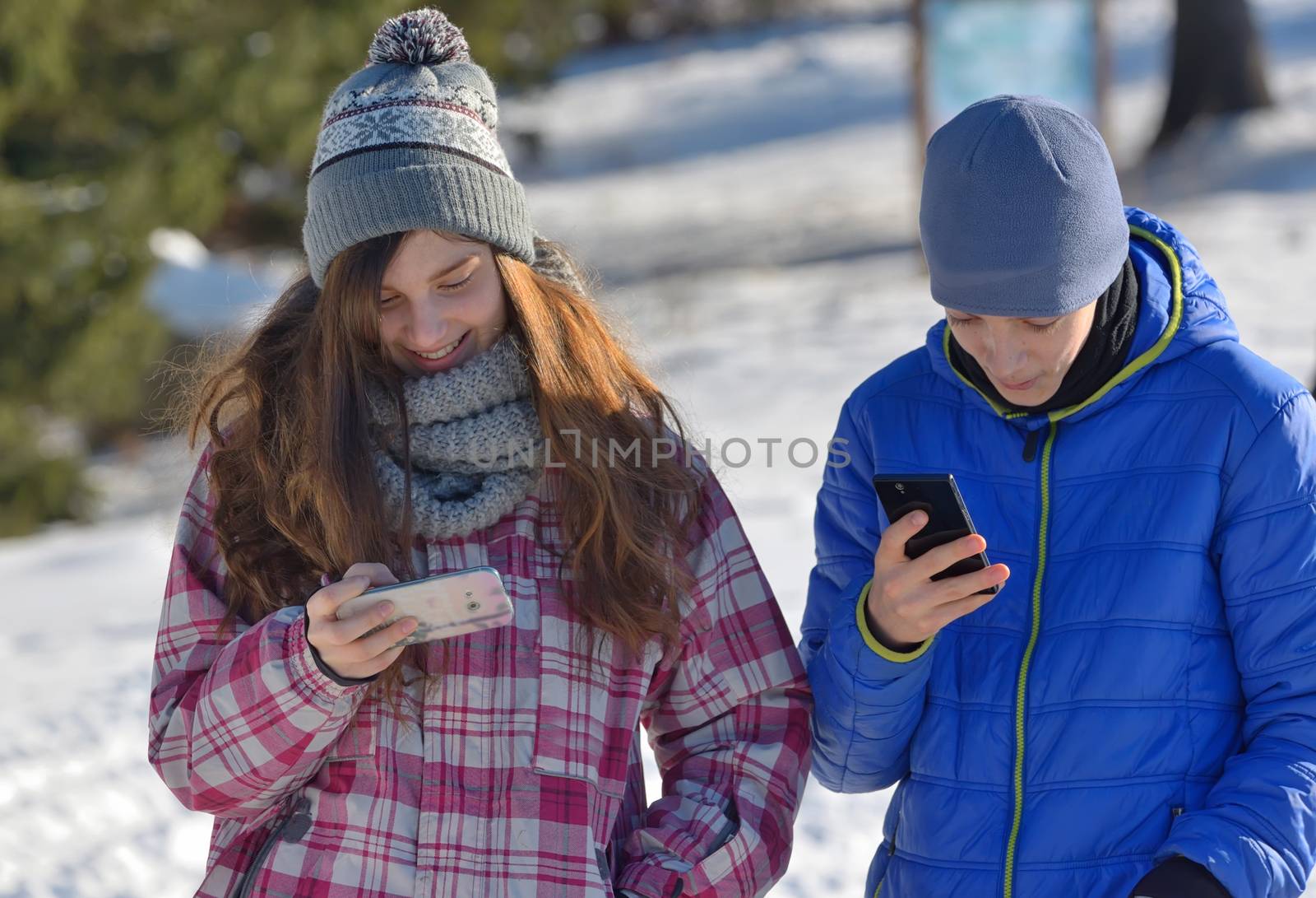 Kids have fun with Smartphone in winter forest