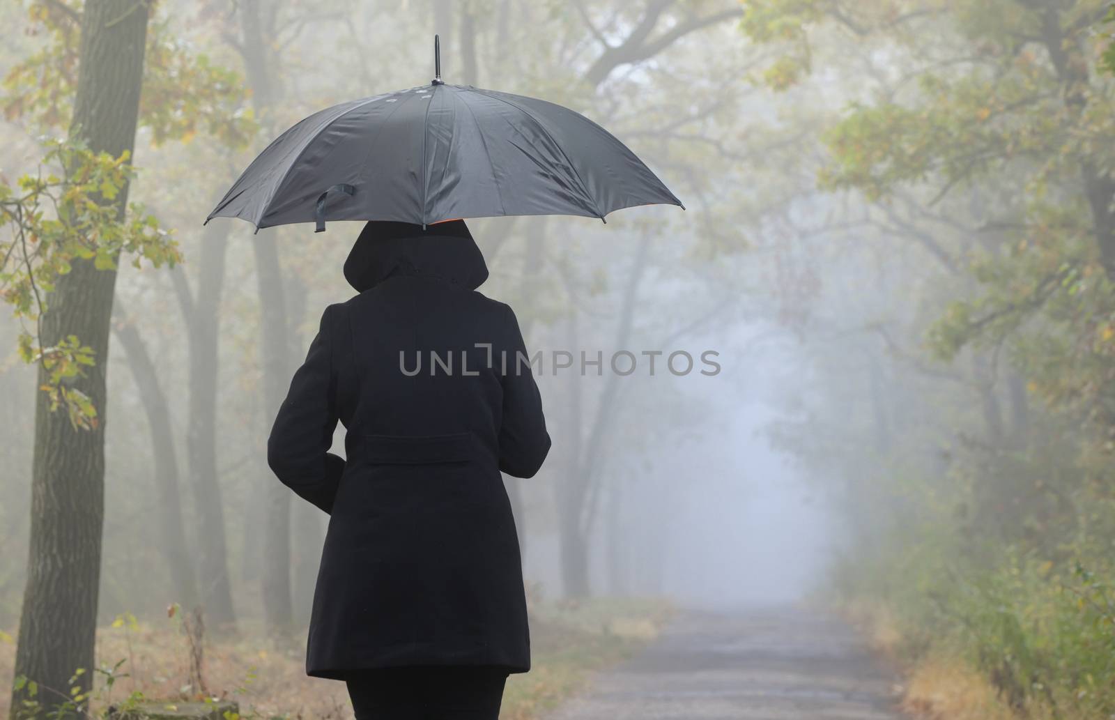 Depressed woman with red umbrella and foggy forest