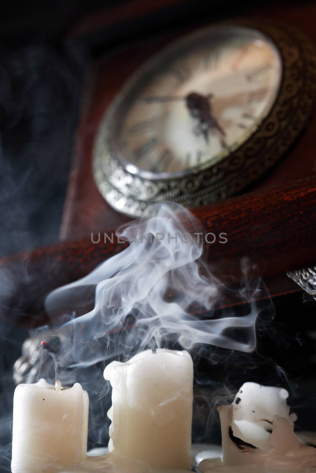 Vintage still life with extinguished candles near old clock