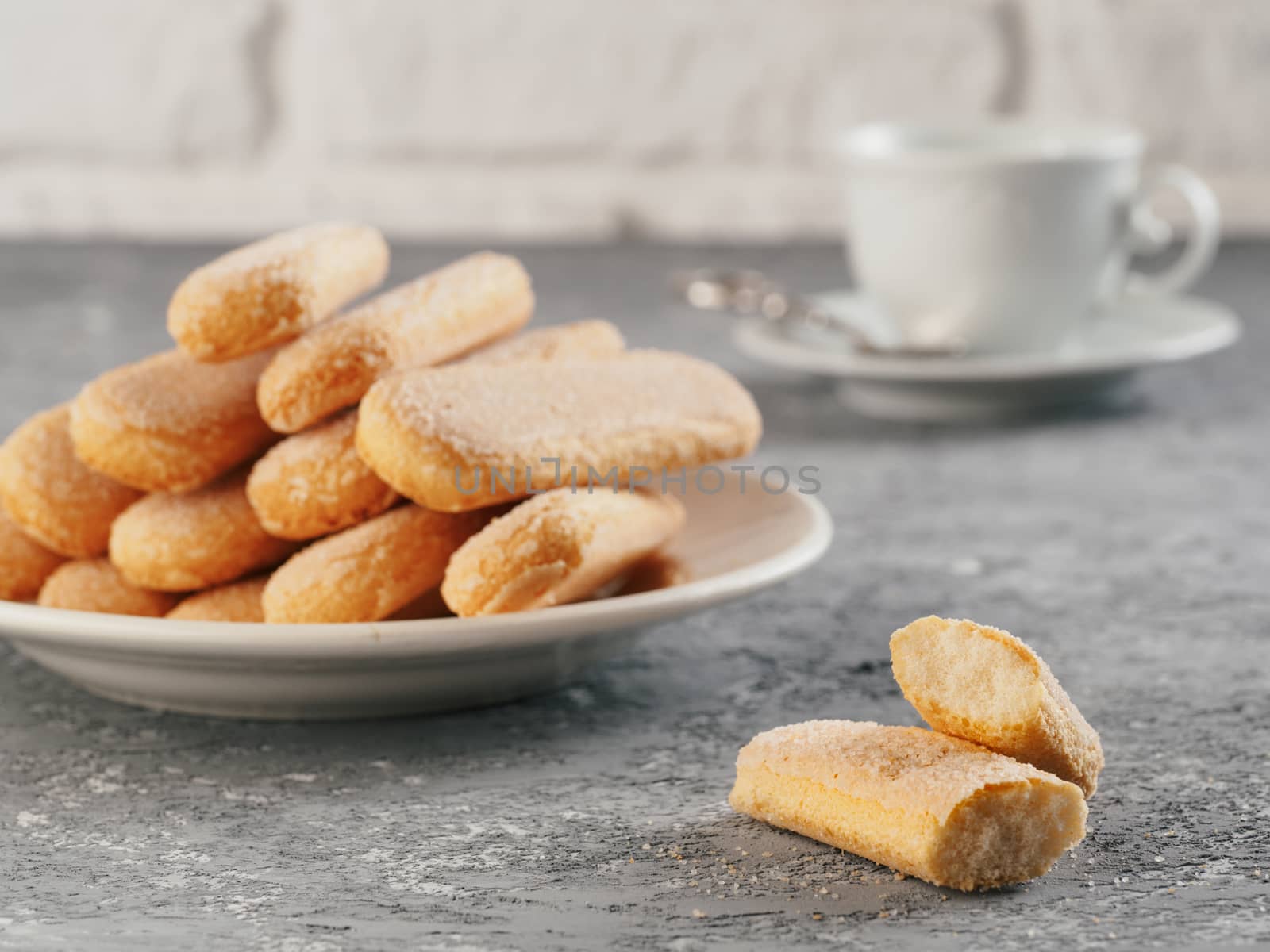 Italian cookie savoiardi and cup of coffee. Close up view of ladyfinger biscuit cookie on gray concrete background. Copy space.