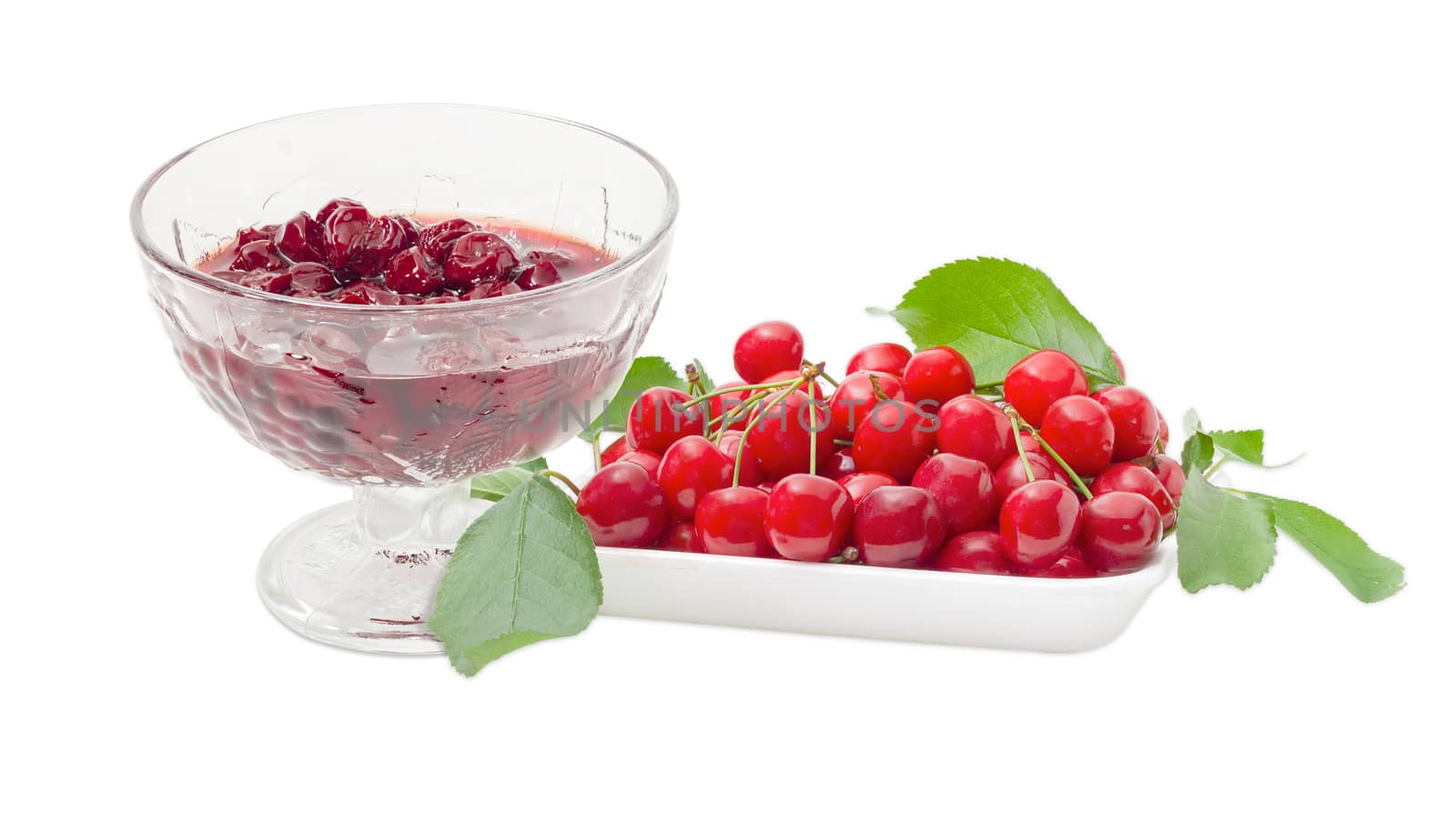 Cherry jam with whole fruits in the glass dessert stem bowl and fresh cherries with the stalks and leaves in in the foam food container beside on a light background
