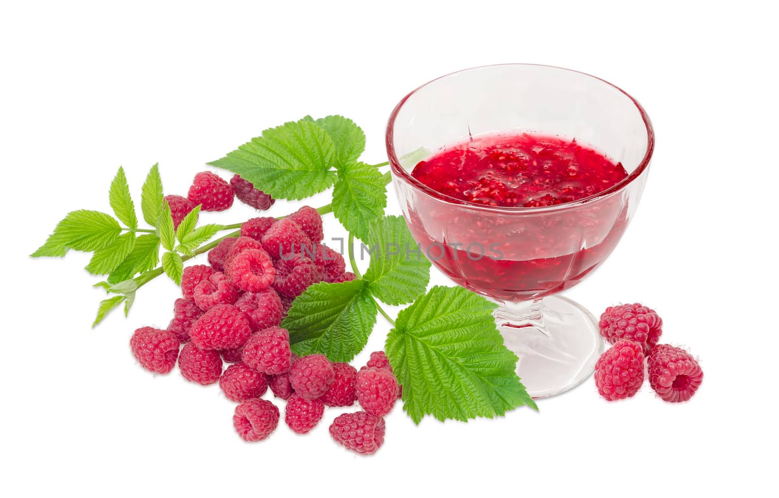 Raspberry jam in the glass dessert stem bowl against of the fresh cultivated red raspberries and raspberry branch with leaves on a light background
