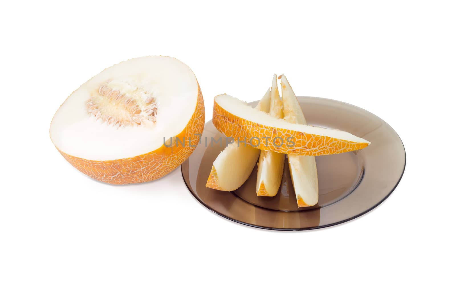 Several slices of the ripe melon on the dark glass dish and half of melon with seeds on a light background
