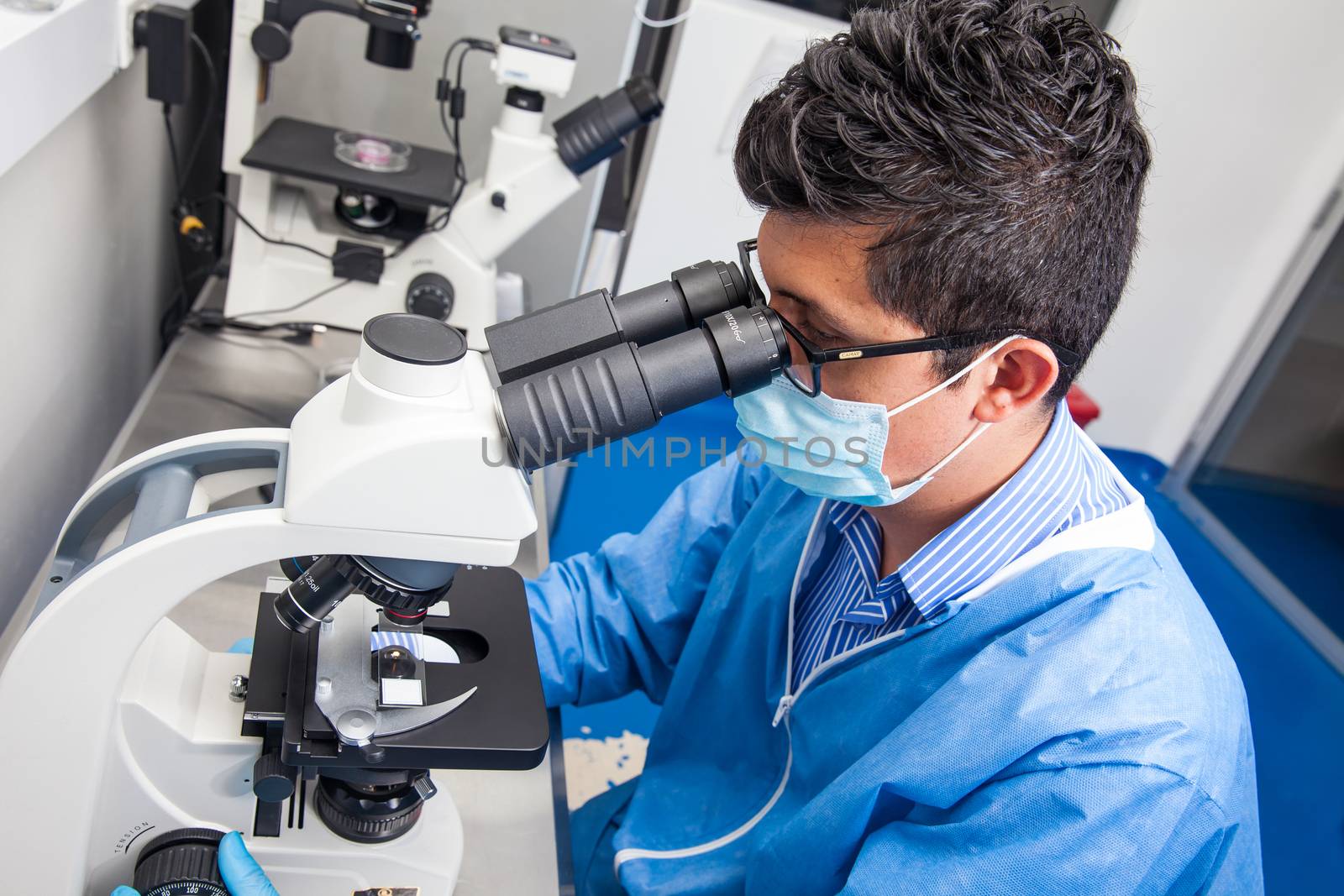 Young male scientist looking at slides under the microscope