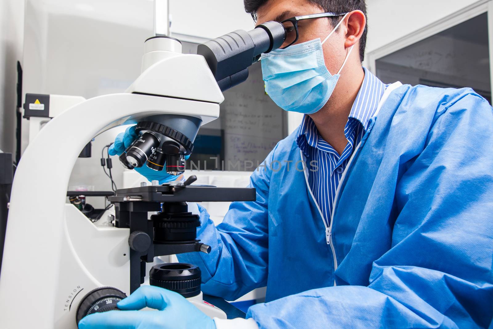 Young male scientist looking at slides under the microscope