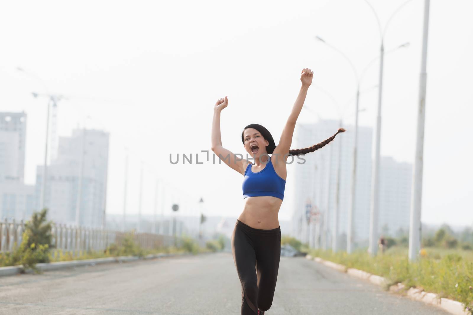 Low angle view of young female athlete crossing finish line against clear blue sky.