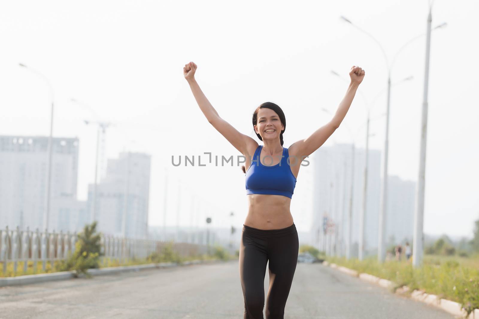 Low angle view of young female athlete crossing finish line against clear blue sky by 3KStudio