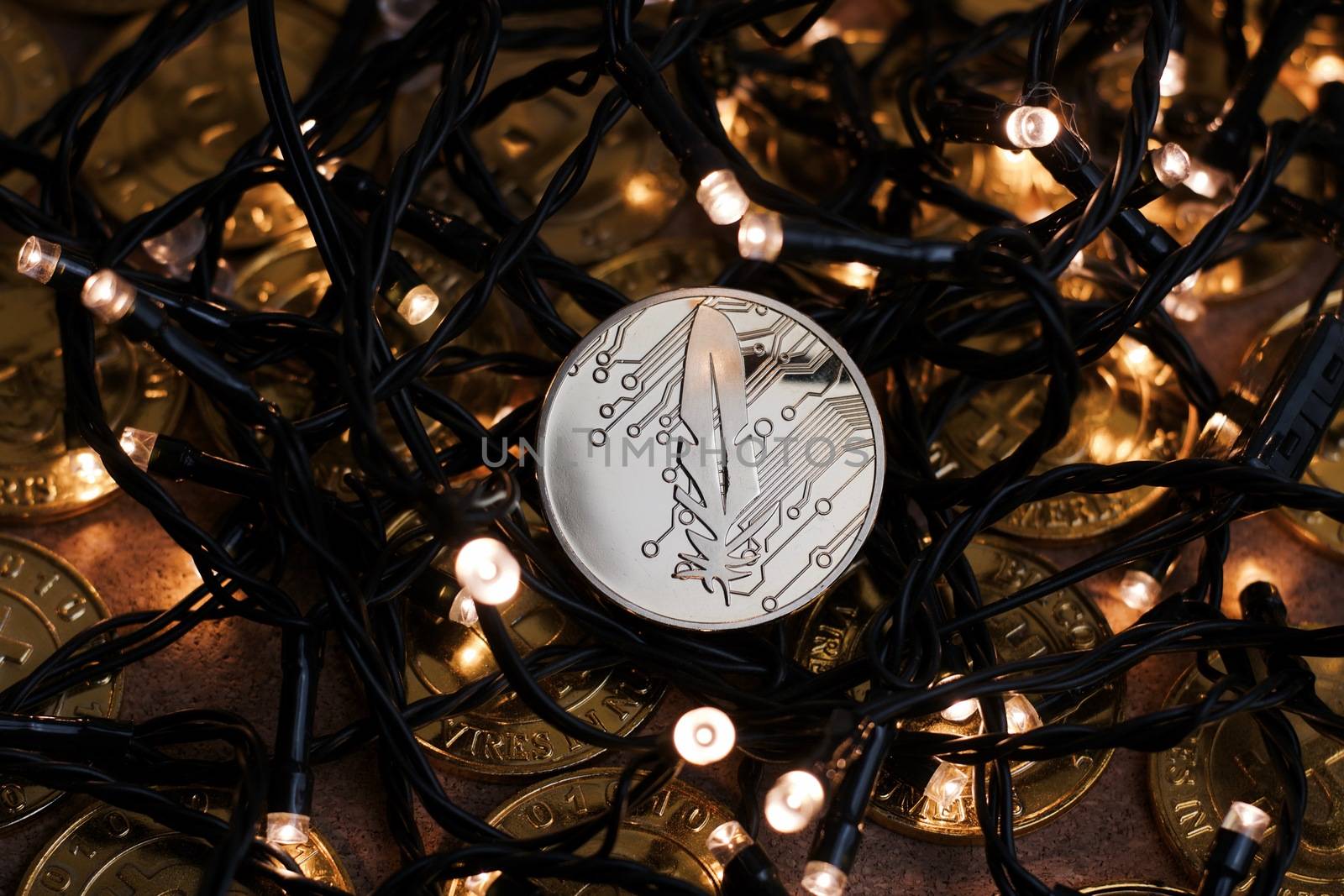Digital currency physical metal gold feather coin near the light. Christmas cryptocurrency concept.