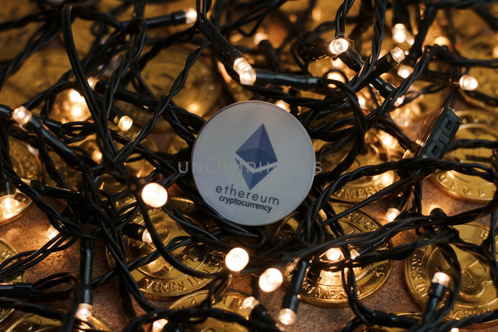 Digital currency physical grey ethereum coin near lights. Cryptocurrency christmas concept.