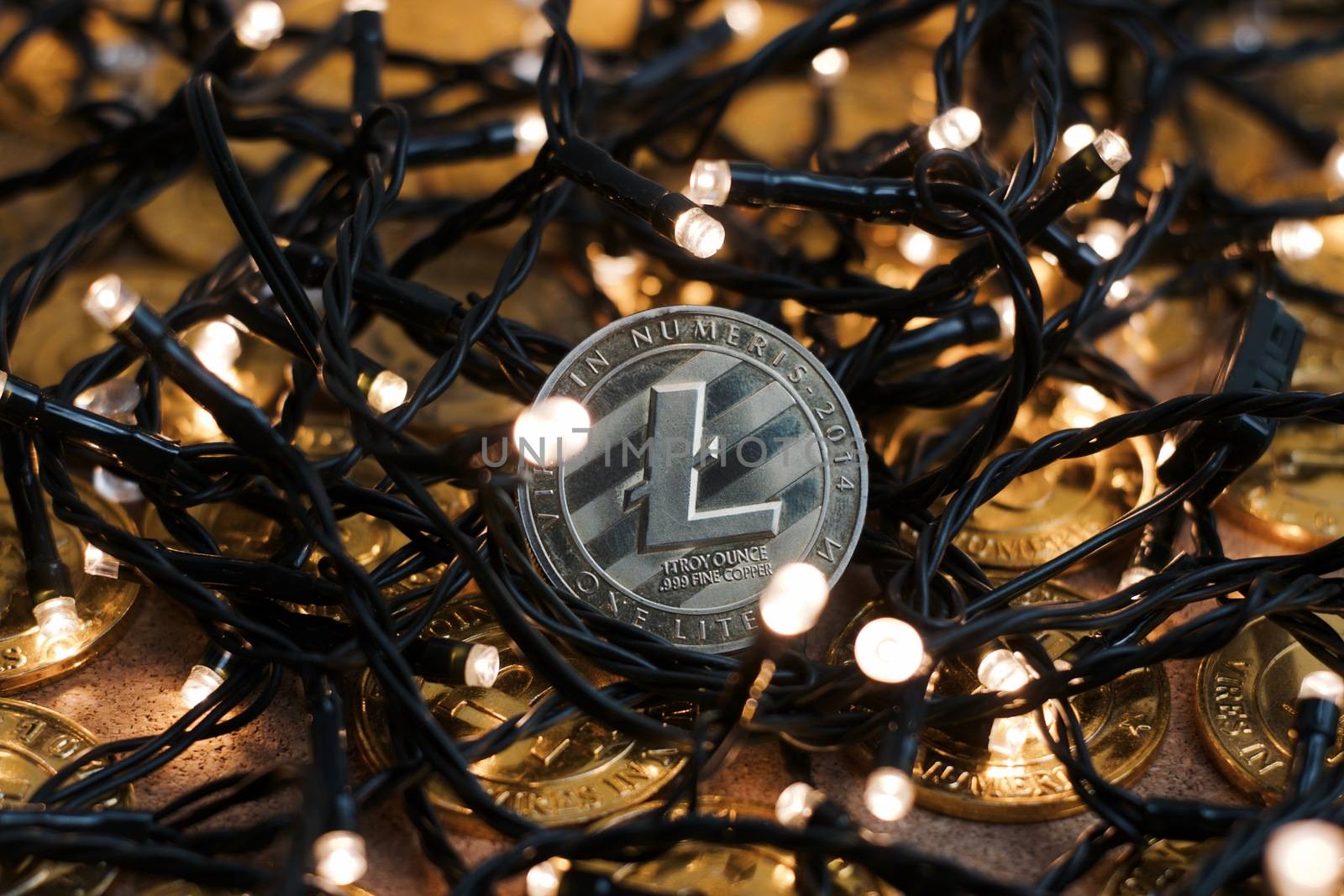 Digital currency physical metal Litecoin coin on the christmas lights concept.