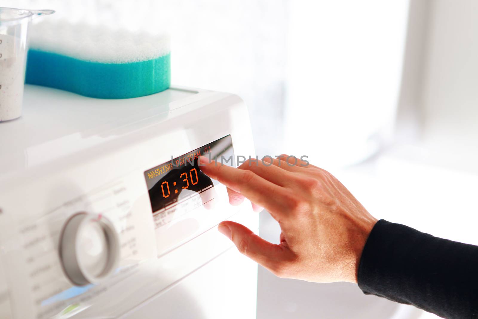 man choosing program for washing machine by ssuaphoto