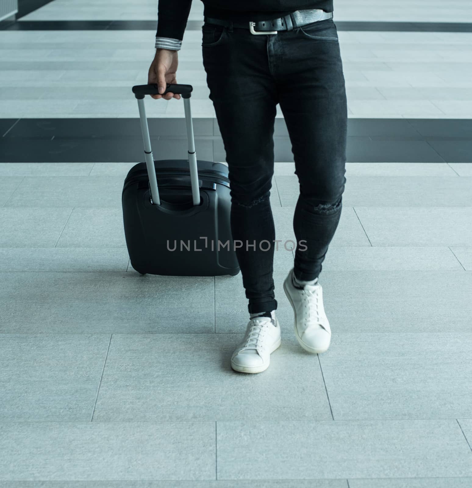 Man walking with wheeled bag at airport terminal