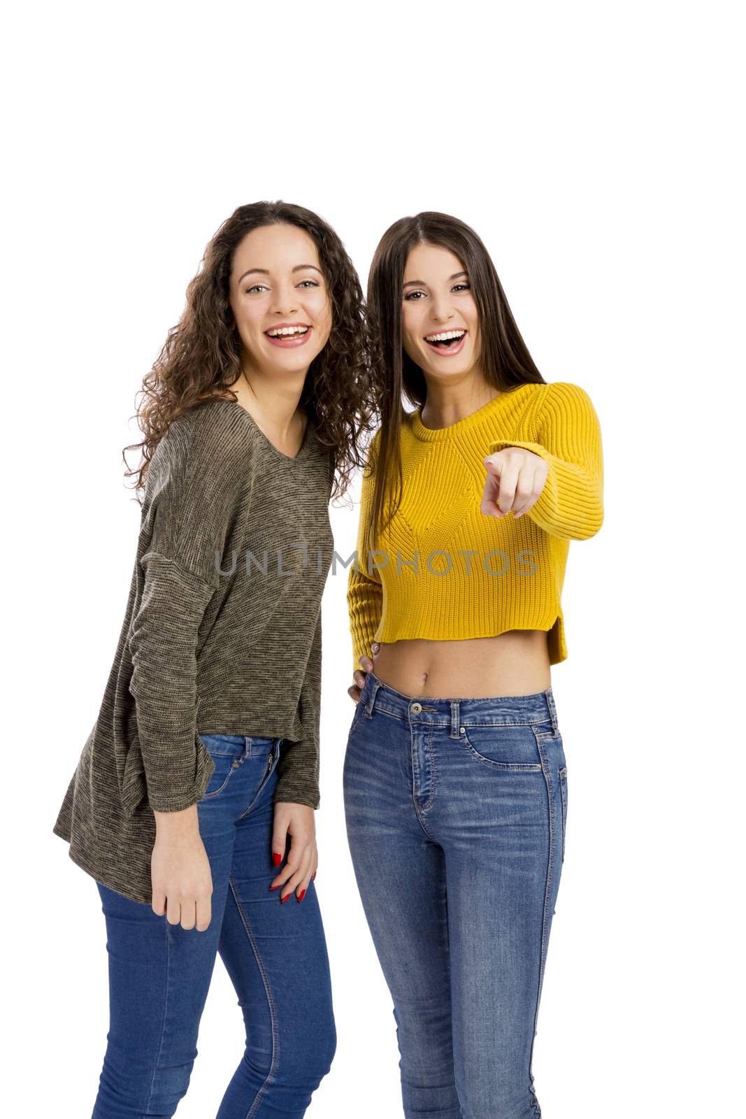 Studio portrait of two beautiful girls pointing and looking to the camera