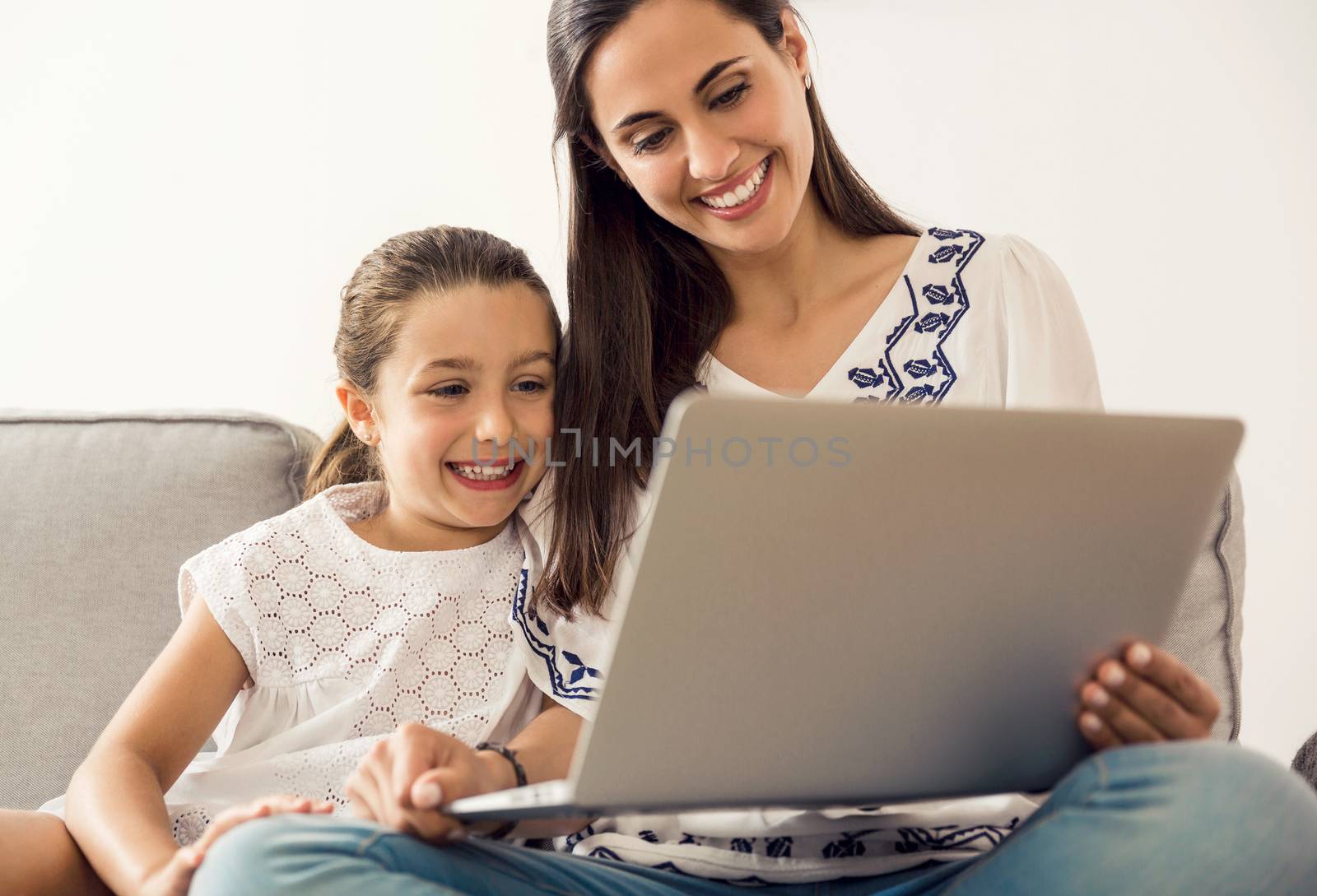 Mom teaching Daughter working with a a laptop at home