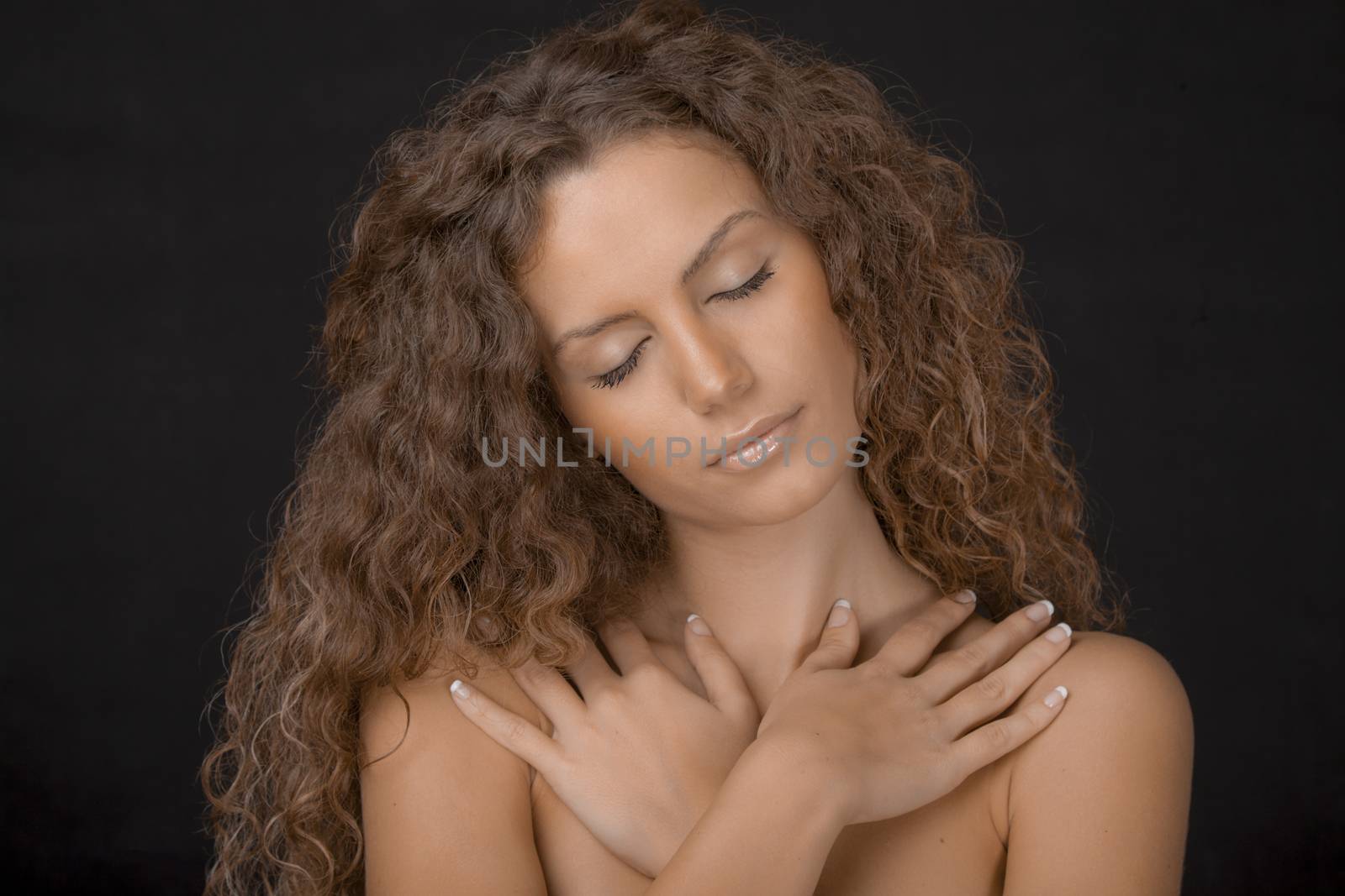 A beauty shot of a gorgeous young female with curly brown hair. Eyes closed.