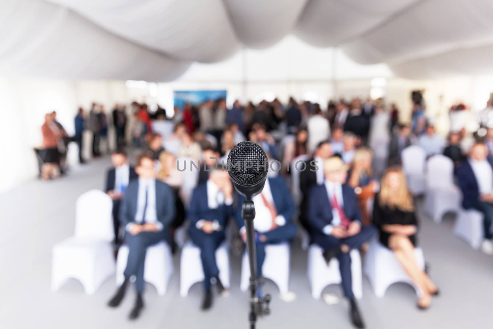 Microphone in focus against blurred audience. Participants at the business or professional conference.